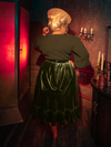 The Victorian Velvet Bustle Skirt in Olive, with its haunting beauty, is displayed by captivating models from the gothic clothing brand La Femme en Noir.