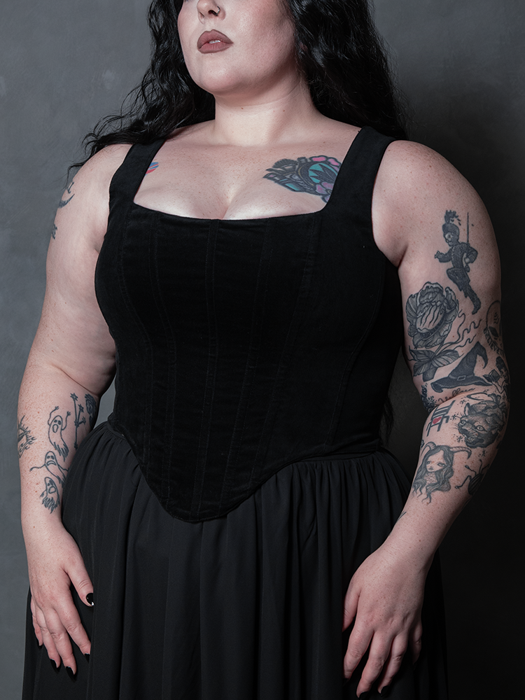 A side angle of the Countess velvet corset in pitch black, highlighting the dramatic hourglass tailoring and luxurious, touchable fabric.
