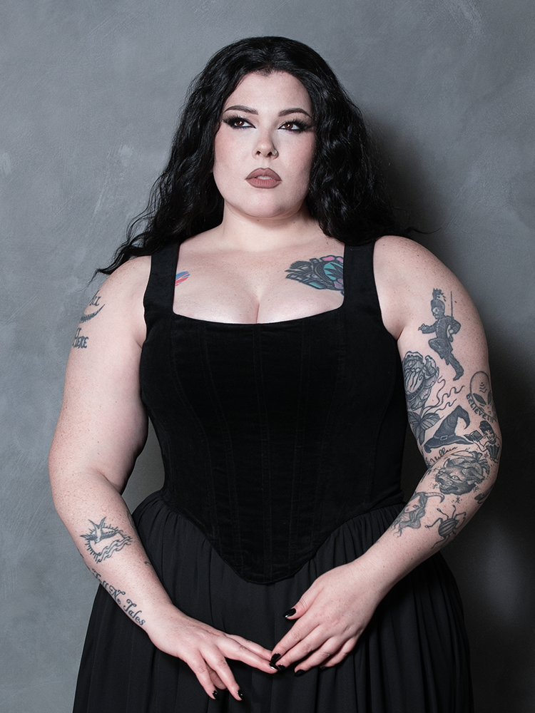 A female model evokes timeless gothic glamour wearing an exquisite black velvet corset with an enchanting, romantic allure.