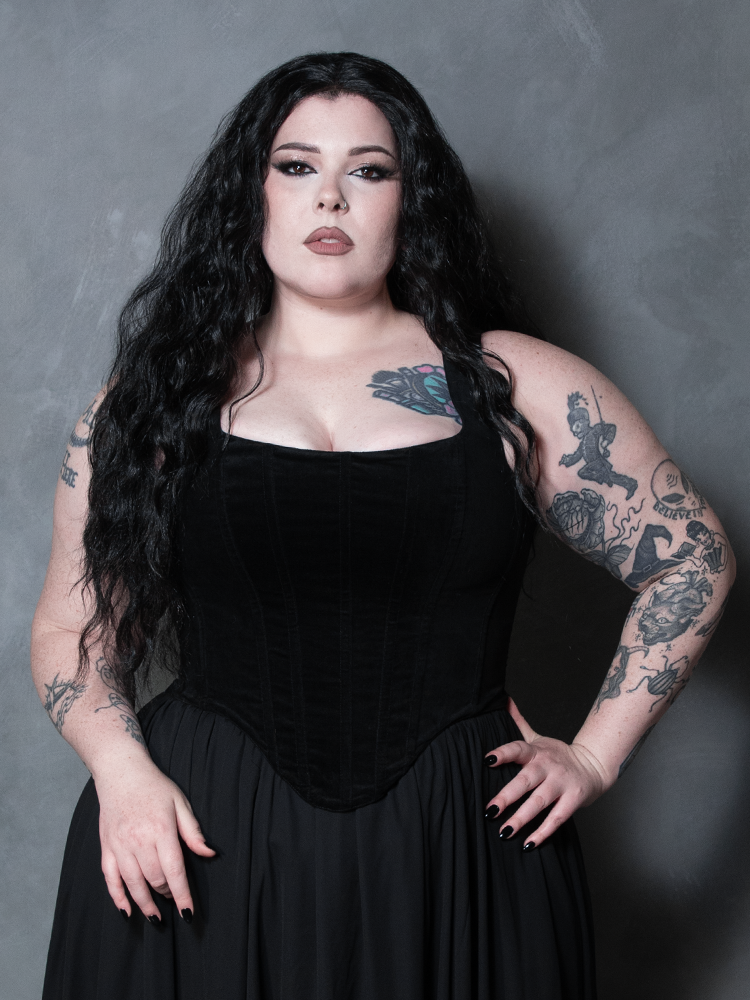 A model with dark makeup and romantic styling poses confidently in the Countess Black Velvet Corset, embodying fierce, dark elegance.