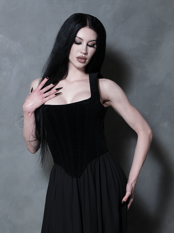 A female model pairs modern nu-goth aesthetics with classic dark glamour wearing a plush black velvet corset top.