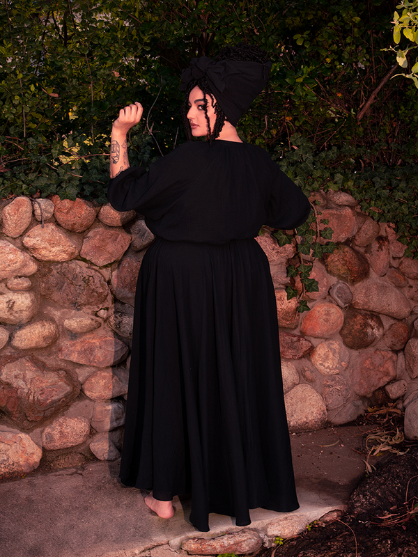 The hemline of this gothic clothing icon trails like midnight tales whispered to the earth.