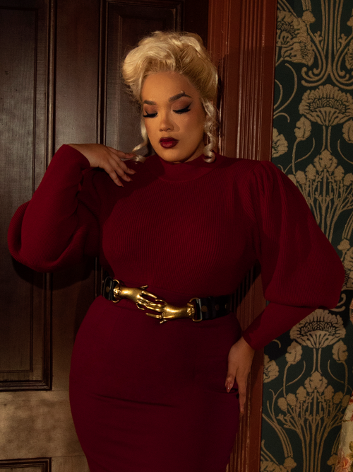 Bold and breathtaking, this crimson Victorian cycling pullover features a high neckline, puffed sleeves, and delicate pleats for a dramatic touch of gothic romance.

