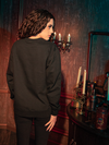 The haunting beauty of the CRIMSON PEAK™ Allerdale Hall Sweatshirt in Black comes to life as models show it off for La Femme en Noir, the renowned gothic clothing brand.
