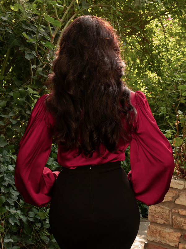 In deep red satin, she commands attention, her blouse an ode to confidence wrapped in Victorian grace.
