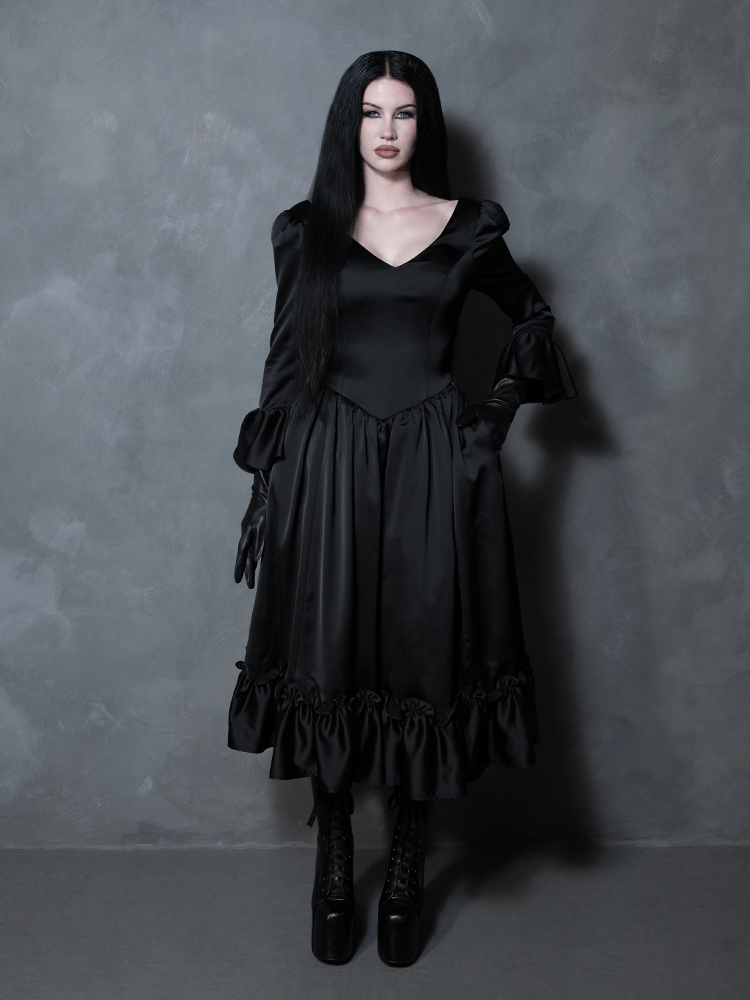 A gorgeous representation of dark elegance, a female model wears a sleek black satin dress tailored for the modern Victorian Goth.