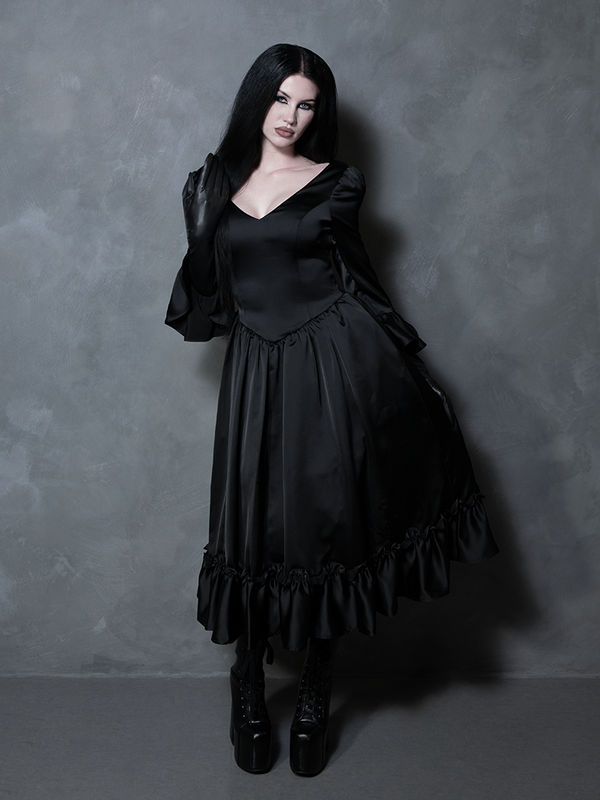 Wrapped in luxury and dark romance, a female model displays an absolute vision of gothic glamour in a black satin dress.