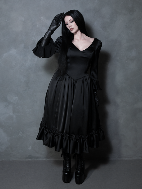 The perfect blend of dark elegance and antique romance, a female model showcases an exquisite black satin gothic dress.