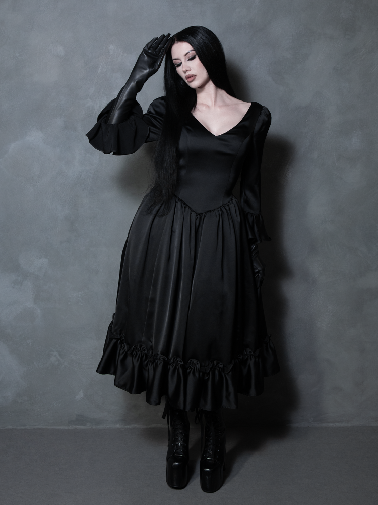 The perfect blend of dark elegance and antique romance, a female model showcases an exquisite black satin gothic dress.
