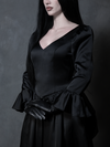 A female model beautifully captures a mood of poetic melancholy and gothic glamour while wearing a dramatic black satin gown.