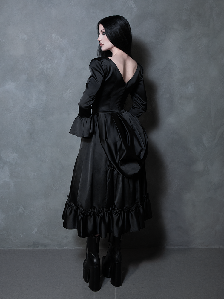 Perfect for the lover of dark elegance, a female model effortlessly showcases a romantic black satin Victorian Goth dress.