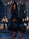 Adrift in the haunting candlelight, the mesmerizing damsel showcases the Velvet Dreams of Darkness Satin Bustle Dress, a creation born from the shadows of La Femme en Noir.