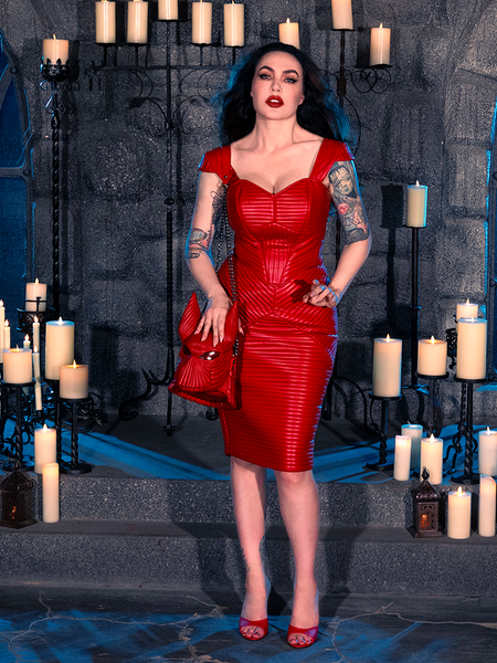 Micheline Pitt captures the enchantment of gothic clothing while wearing the BRAM STOKER'S DRACULA Quilted Order of the Dragon Armor Skater Skirt in Blood Red Vegan Leather, sourced from La Femme en Noir, within a candlelit dungeon.
