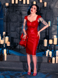In the dimly lit dungeon, Micheline Pitt embodies gothic fashion, wearing the BRAM STOKER'S DRACULA Quilted Order of the Dragon Armor Skater Skirt in Blood Red Vegan Leather, a remarkable piece from La Femme en Noir's goth clothing line.