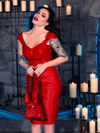 Micheline Pitt showcases her affinity for gothic attire in a candle-lit dungeon, elegantly modeling the BRAM STOKER'S DRACULA Quilted Order of the Dragon Armor Skater Skirt in Blood Red Vegan Leather from La Femme en Noir's gothic clothing collection.