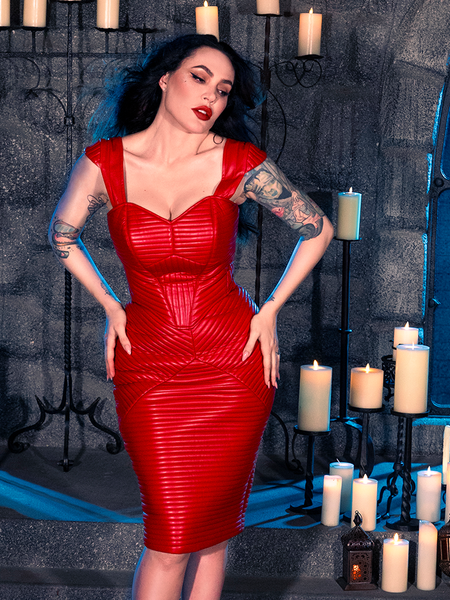 Micheline Pitt strikes a dramatic pose in a dimly lit dungeon, donning the BRAM STOKER'S DRACULA Quilted Order of the Dragon Armor Skater Skirt in Blood Red Vegan Leather, sourced from La Femme en Noir, a renowned gothic clothing brand.