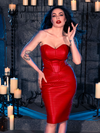 Wearing the BRAM STOKER'S DRACULA Quilted Order of the Dragon Armor Skater Skirt in Blood Red Vegan Leather, Micheline Pitt exudes an air of mystery while in a candle-lit dungeon, embracing the style of La Femme en Noir's goth clothing.