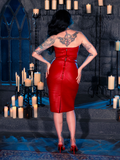 Micheline Pitt, cloaked in the BRAM STOKER'S DRACULA Quilted Order of the Dragon Armor Skater Skirt in Blood Red Vegan Leather, courtesy of La Femme en Noir's gothic fashion collection, elegantly poses in a candle-lit dungeon.