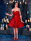 In a candlelit dungeon, Micheline Pitt showcases her style with the BRAM STOKER'S DRACULA Quilted Order of the Dragon Armor Skater Skirt in Blood Red Vegan Leather by La Femme en Noir, a renowned gothic clothing brand.