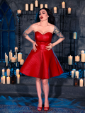 Donning the BRAM STOKER'S DRACULA Quilted Order of the Dragon Armor Skater Skirt in Blood Red Vegan Leather, Micheline Pitt showcases her love for gothic attire from the iconic brand La Femme en Noir in a dungeon lit by candles.