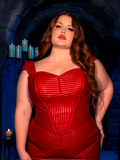 Red haired model brings the art of gothic clothing to life with the BRAM STOKER'S DRACULA Quilted Order of the Dragon Armor Bustier Top in Blood Red Vegan Leather, as she poses in a candle-lit dungeon, embodying the enchantment of La Femme en Noir.