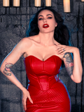 With the BRAM STOKER'S DRACULA Quilted Order of the Dragon Armor Bustier Top in Blood Red Vegan Leather, Micheline Pitt creates a captivating scene in a candle-lit dungeon, embodying the essence of gothic fashion, courtesy of La Femme en Noir, a goth clothing specialist.
