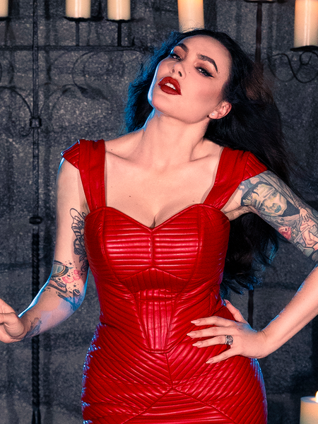 Micheline Pitt sets the mood in a candle-lit dungeon, exuding the essence of gothic fashion with the BRAM STOKER'S DRACULA Quilted Order of the Dragon Armor Bustier Top in Blood Red Vegan Leather, a striking piece from the goth clothing collection of La Femme en Noir.