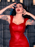 Clad in the BRAM STOKER'S DRACULA Quilted Order of the Dragon Armor Bustier Top in Blood Red Vegan Leather, Micheline Pitt unveils her gothic elegance within the candle-lit dungeon, thanks to the fashion-forward label, La Femme en Noir.