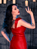 Micheline Pitt, draped in the BRAM STOKER'S DRACULA Quilted Order of the Dragon Armor Bustier Top in Blood Red Vegan Leather, embodies the essence of gothic clothing within a candle-lit dungeon, thanks to La Femme en Noir, a gothic fashion brand.