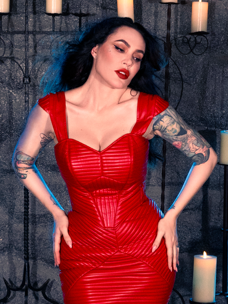 Wearing the BRAM STOKER'S DRACULA Quilted Order of the Dragon Armor Bustier Top in Blood Red Vegan Leather, Micheline Pitt exudes an air of mystery while in a candle-lit dungeon, embracing the style of La Femme en Noir's goth clothing.