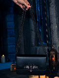 The BRAM STOKER'S DRACULA Gargoyle Sculpture Quilted Crossbody Bag in Black takes center stage, encircled by the enchanting dance of flickering candles, a creation brought to life by La Femme en Noir.