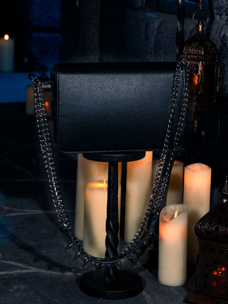 In the company of flickering candles, the haunting allure of the Gargoyle Sculpture Quilted Crossbody Bag in Black from La Femme en Noir's BRAM STOKER'S DRACULA collection comes to the fore.