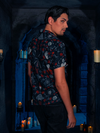 The candlelit dungeon provides a captivating setting as the model dons the BRAM STOKER'S DRACULA Button Up Short Sleeve Shirt in Dracula Novelty Print.