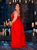 With the BRAM STOKER'S DRACULA Lucy Bustier Gown and Matching Cape in Fire Orange, a female model brings the art of gothic fashion to life in a candle-lit dungeon, capturing the enchantment of La Femme en Noir's goth clothing.