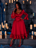 Surrounded by candles in a dimly lit dungeon room, the beautiful model accentuates her elegance by wearing the BRAM STOKER'S DRACULA Mina Satin Bustle Dress in Blood Red.