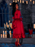 Surrounded by candles, the BRAM STOKER'S DRACULA Mina Satin Bustle Dress in Blood Red looks exquisite on the beautiful model in the dimly lit dungeon room.