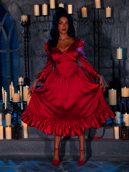 The BRAM STOKER'S DRACULA Mina Satin Bustle Dress in Blood Red looks exquisite as it graces the beautiful model in a dimly lit dungeon room filled with candles.