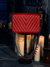 The BRAM STOKER'S DRACULA Gargoyle Sculpture Quilted Crossbody Bag in Blood Red takes center stage, encircled by the enchanting dance of flickering candles, a creation brought to life by La Femme en Noir.