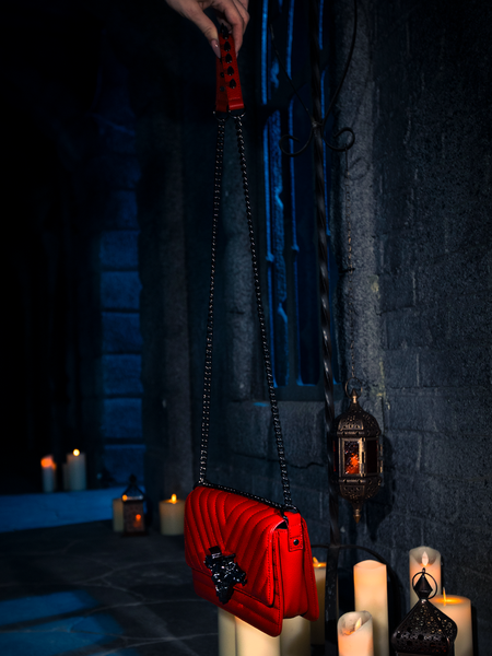 Surrounded by the enchanting flicker of candles, the BRAM STOKER'S DRACULA Gargoyle Sculpture Quilted Crossbody Bag in Blood Red finds its home, a creation to behold from the depths of La Femme en Noir.