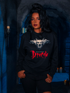 Enveloped by the somber ambiance of a dimly lit dungeon, the human model reveals the Gargoyle Sculpture Sweatshirt in Black, a striking piece from La Femme en Noir's BRAM STOKER'S DRACULA collection.