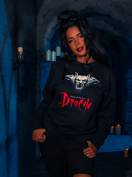In the eerie ambiance of a poorly illuminated dungeon, the earthly model showcases the Gargoyle Sculpture Sweatshirt in Black, part of La Femme en Noir's BRAM STOKER'S DRACULA collection.