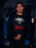 Within the dimly illuminated dungeon, the earthly model elegantly showcases the Gargoyle Sculpture Sweatshirt in Black, a haunting garment from La Femme en Noir's BRAM STOKER'S DRACULA collection.