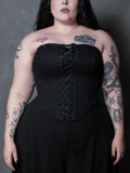 A female model embodies pure gothic glamour, wearing a structured black cotton sateen corset that captures the essence of dark elegance.
