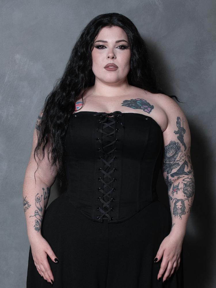A beautiful vision of Victorian goth sophistication unfolds as a female model wears a deep black cotton corset.