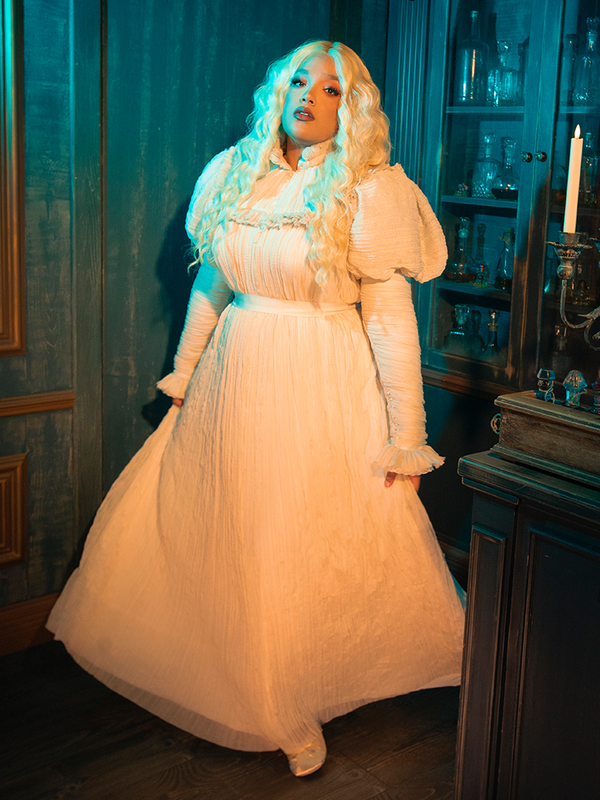 The celestial elegance of the CRIMSON PEAK™ Edith Victorian Gown is undeniable. Its fabric glimmers like the soft light of dawn, casting a glow of purity and grace. The detailed lace is like the intricate patterns of the stars, guiding the wearer through the night with a sense of wonder and beauty.