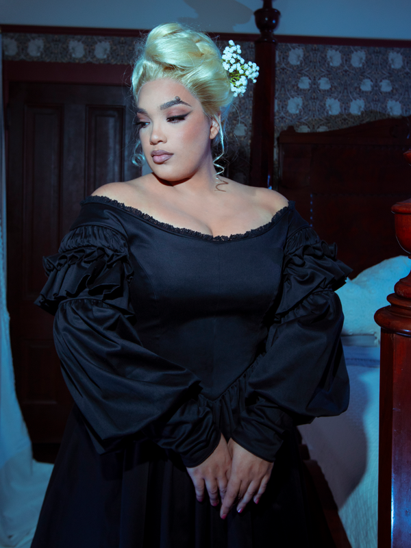 Dressed in the exquisite Ellen Victorian Dress in Black, a female model commands the room with an undeniable aura of dark elegance.