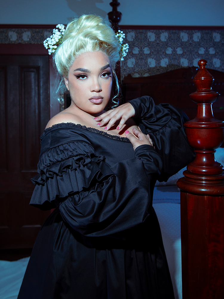 A female model embodies the ultimate vision of gothic glamour, draped in the hauntingly beautiful Ellen Victorian Dress in Black.