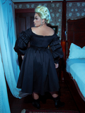 The Ellen Victorian Dress in Black combines old-world charm with modern sophistication. Delicate lace sleeves and a sweeping satin train evoke gothic poetry in motion.