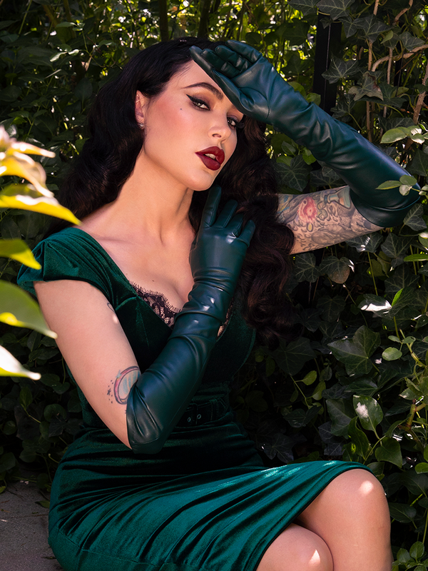 Capturing a spirit of dark romance and sophisticated goth style, a female model wears these luxurious hunter green opera gloves as a statement of gothic glamour.