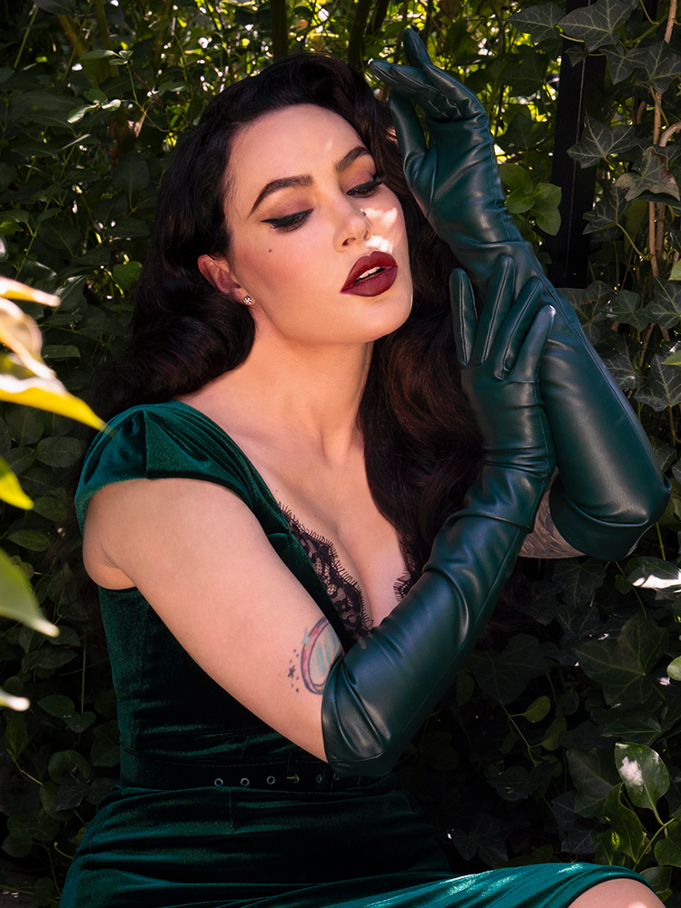 A female model channels ultimate gothic glamour while wearing these dramatic, deep hunter green faux leather opera gloves, adding a touch of timeless mystery to her look.